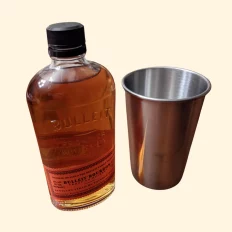 Bulleit bourbon whiskey bottle and metal cup.