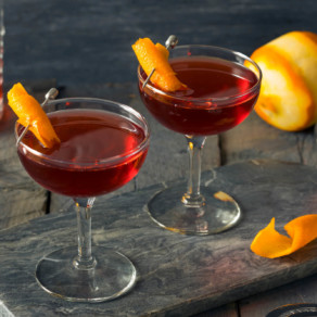 Red boulevadier cocktail in glass decorated with orange peels - Flask & Barrel