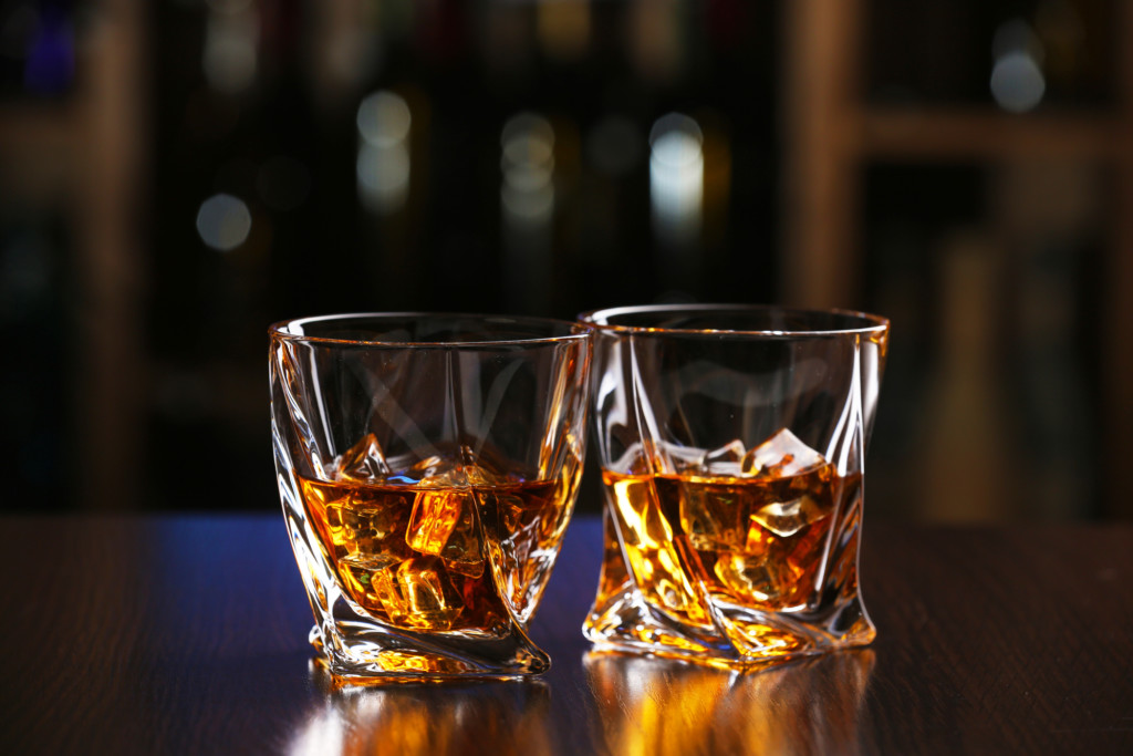 Glasses of whiskey on bar background