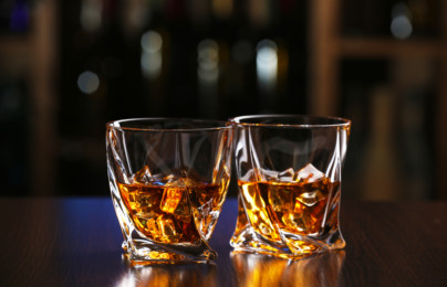 Glasses of whiskey on bar background