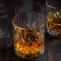 Single malt scotch whiskey in crystal glasses on wooden background