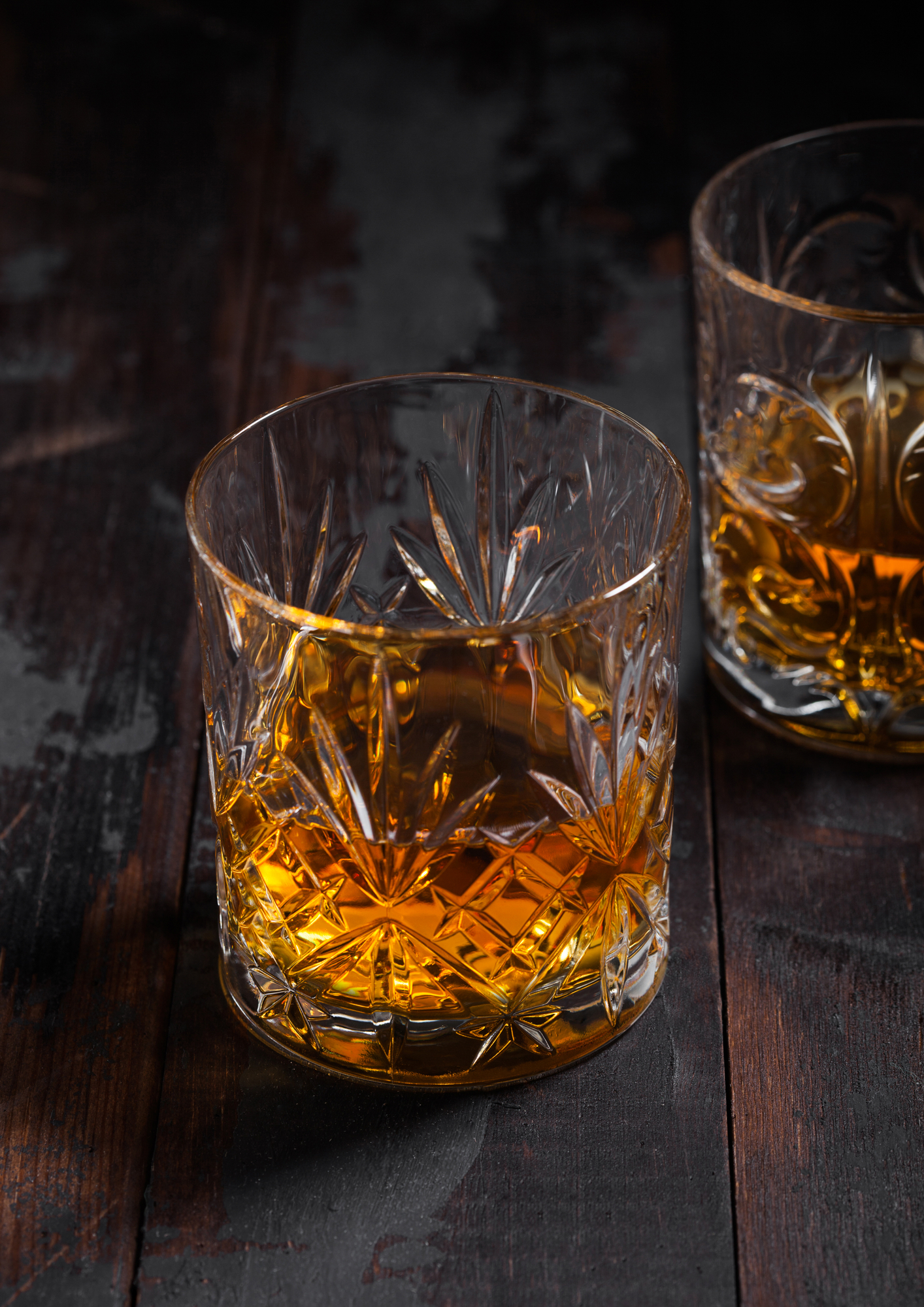 Single malt scotch whiskey in crystal glasses on wooden background