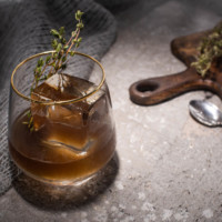 Selective focus of transparent glass with herb, ice cube and whiskey - Flask & Barrel