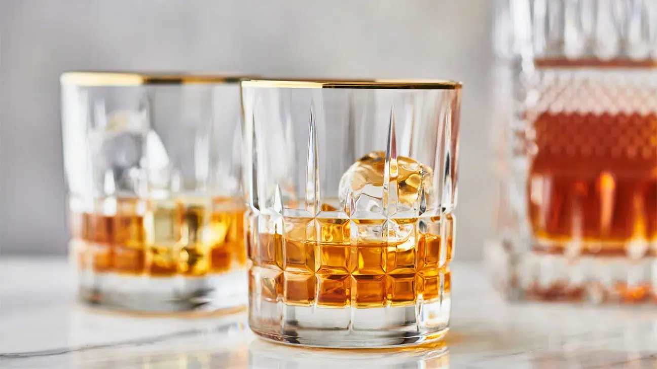 Whiskey glasses with ice on marble surface.