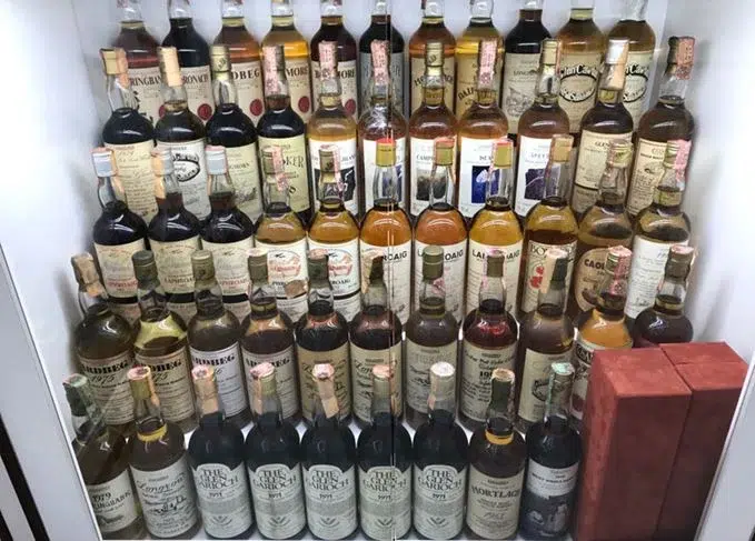 Variety of vintage whiskey bottles on shelves.