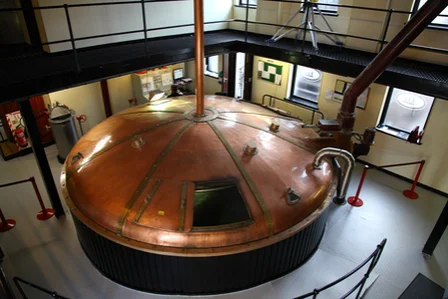 Large copper brewery vat in industrial setting.