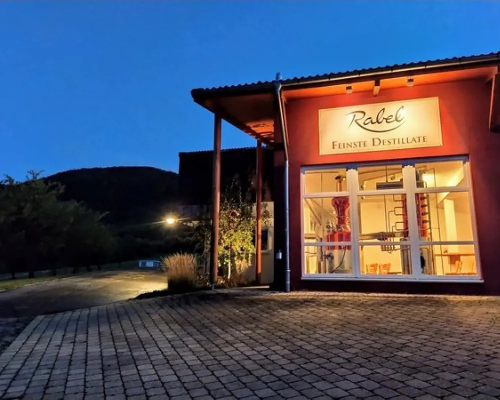 Illuminated storefront at dusk, mountains in the background.