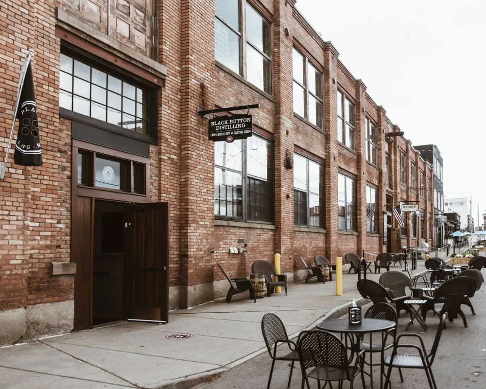 Brick distillery building with outdoor patio seating.