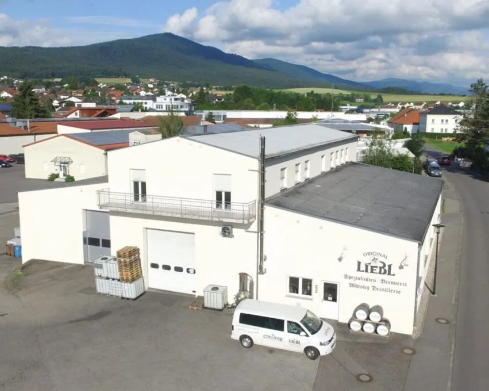 Industrial building with delivery van near mountains.