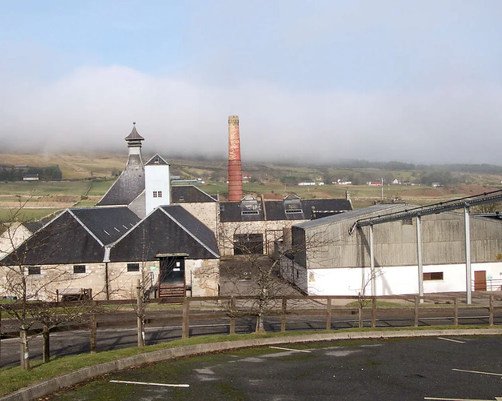Distillery with chimney in misty rural landscape.
