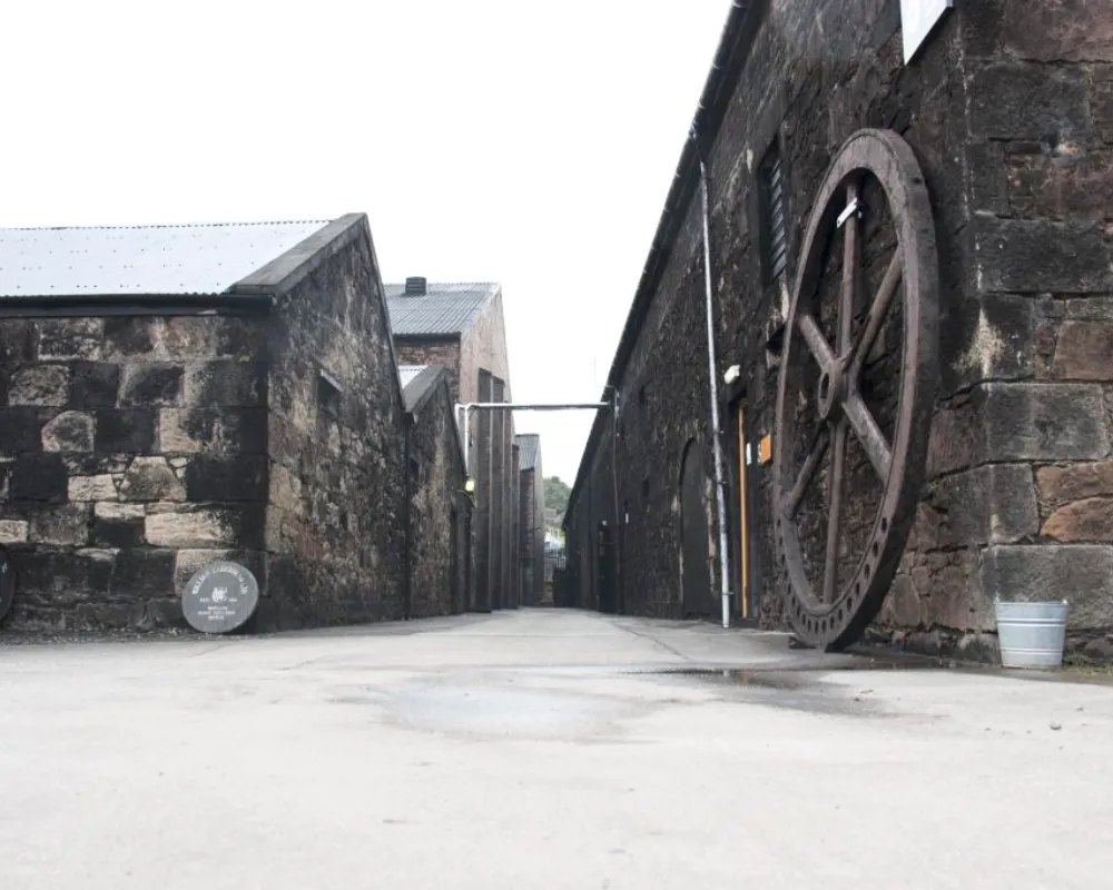 Historic stone building with large wheel on wall.