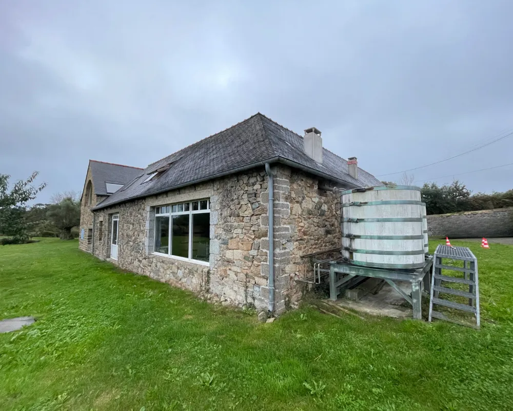 Rural stone cottage with water tank outside.