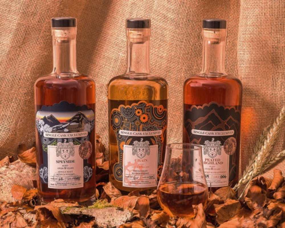 Three whiskey bottles with autumn leaves and a glass.