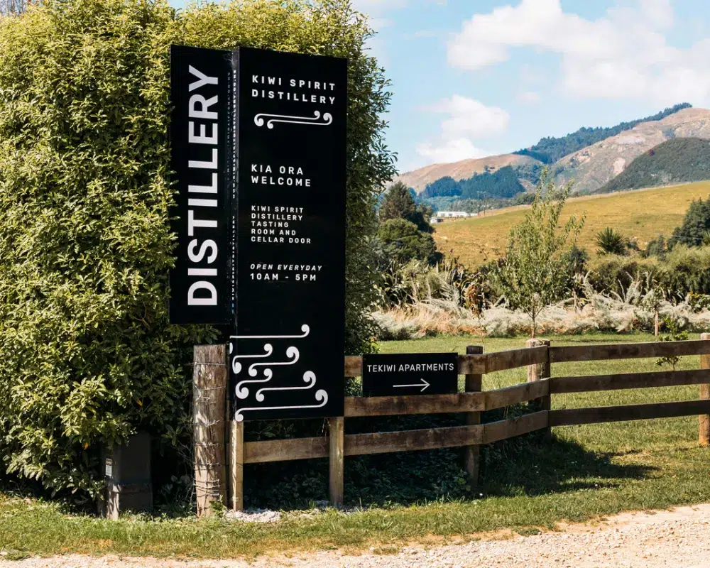 Distillery signboard with scenic countryside background.