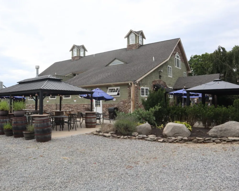 Rustic winery building with outdoor seating and umbrellas.