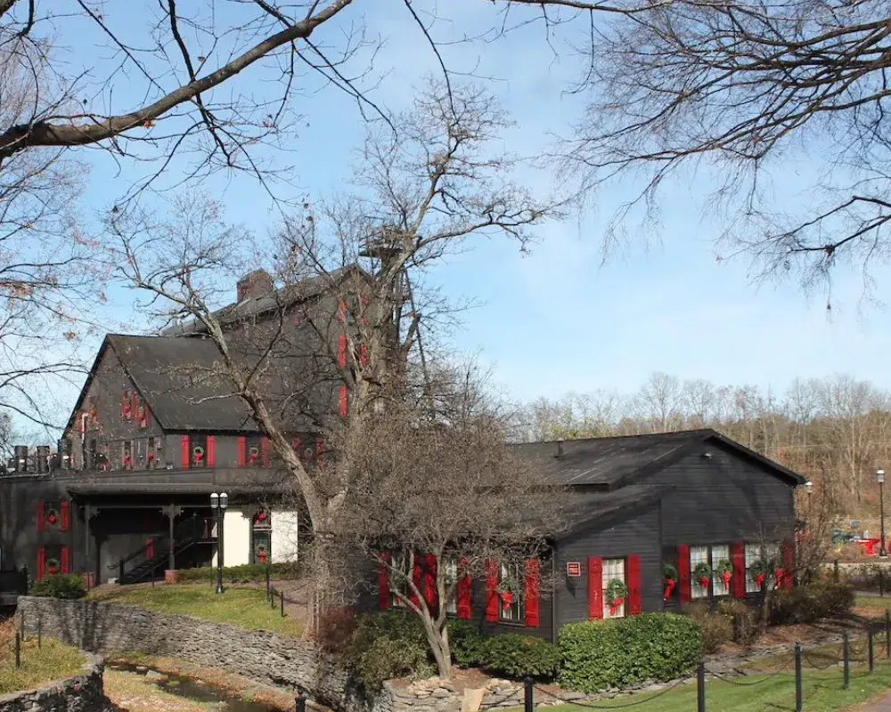 Historic black barn with red accents in rural landscape.