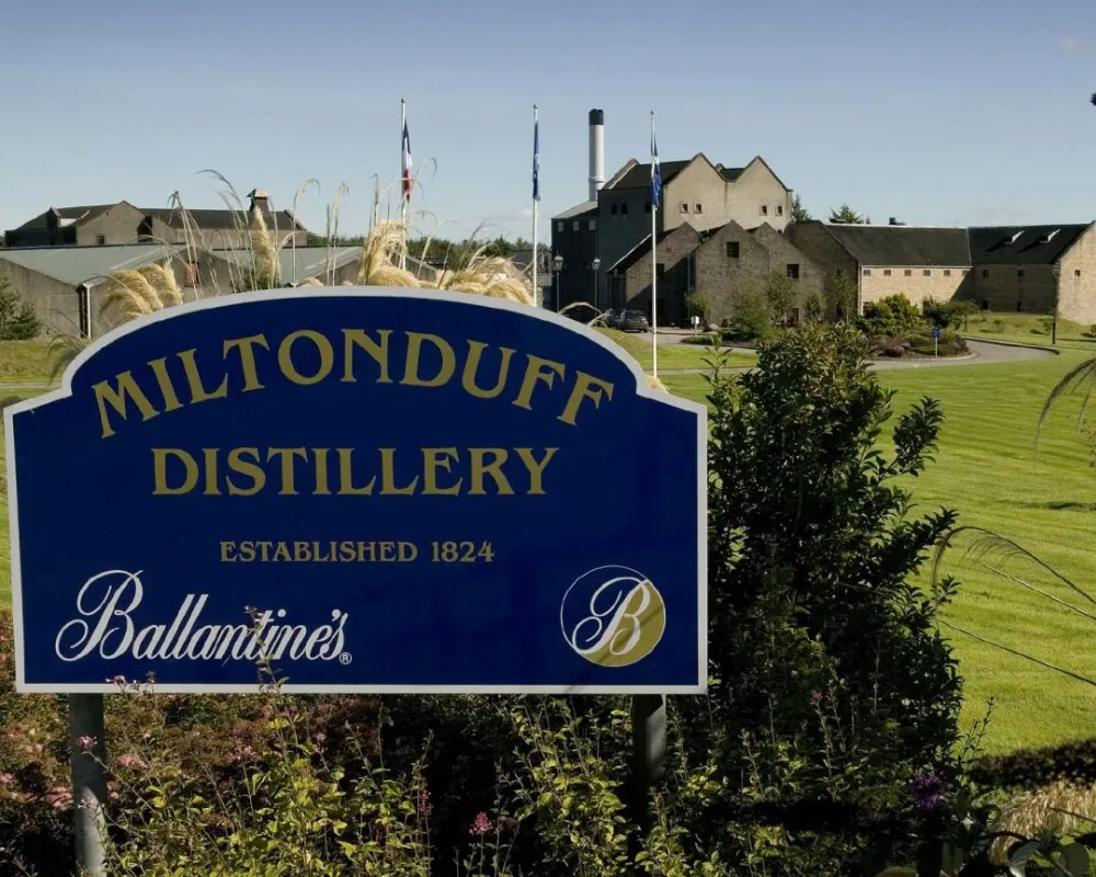 Signage for Miltonduff Distillery, landscape in the background.