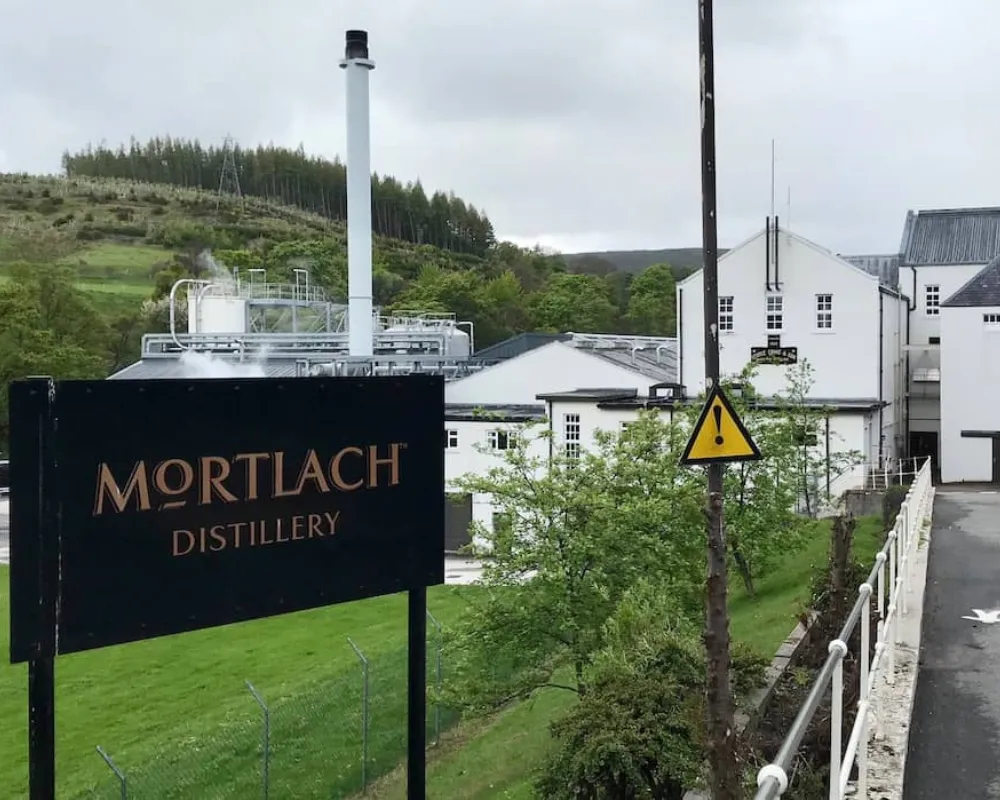 Mortlach Distillery entrance with sign and greenery.