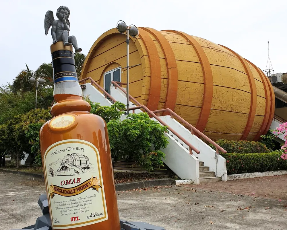 Giant whisky bottle display in front of a barrel-shaped building.