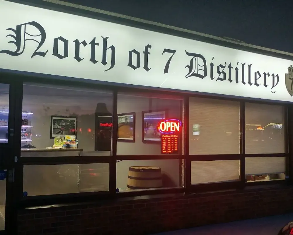 North of 7 Distillery storefront at night with open sign.