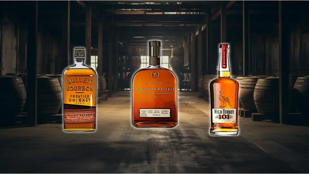 Three bourbon whiskey bottles in a wooden barrel warehouse.