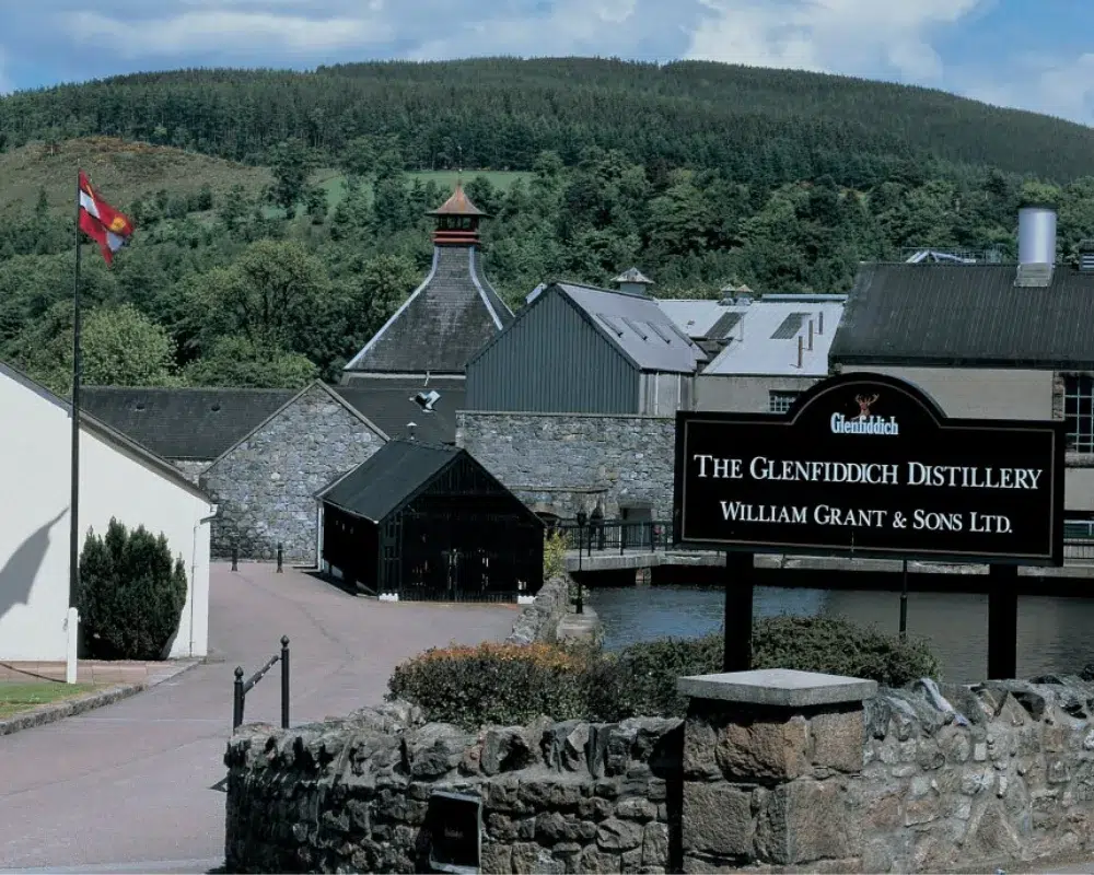 Glenfiddich Distillery exterior in Scotland with sign and hills.