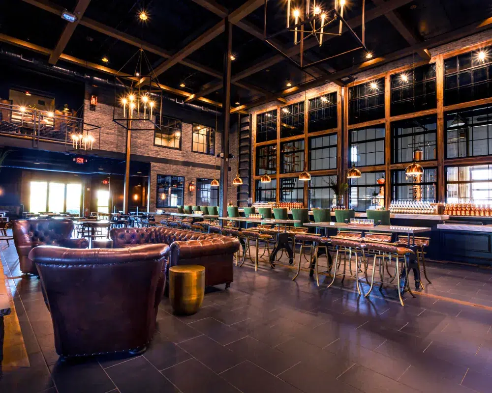Elegant industrial-style bar with leather seating and chandeliers.