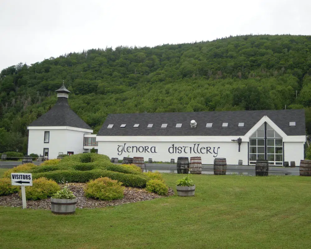 Glenora Distillery building with lush green hill background.