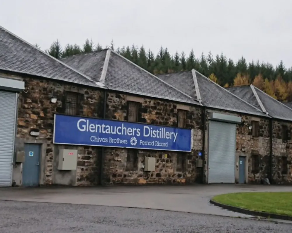 Glentauchers Distillery exterior with stone buildings and sign.