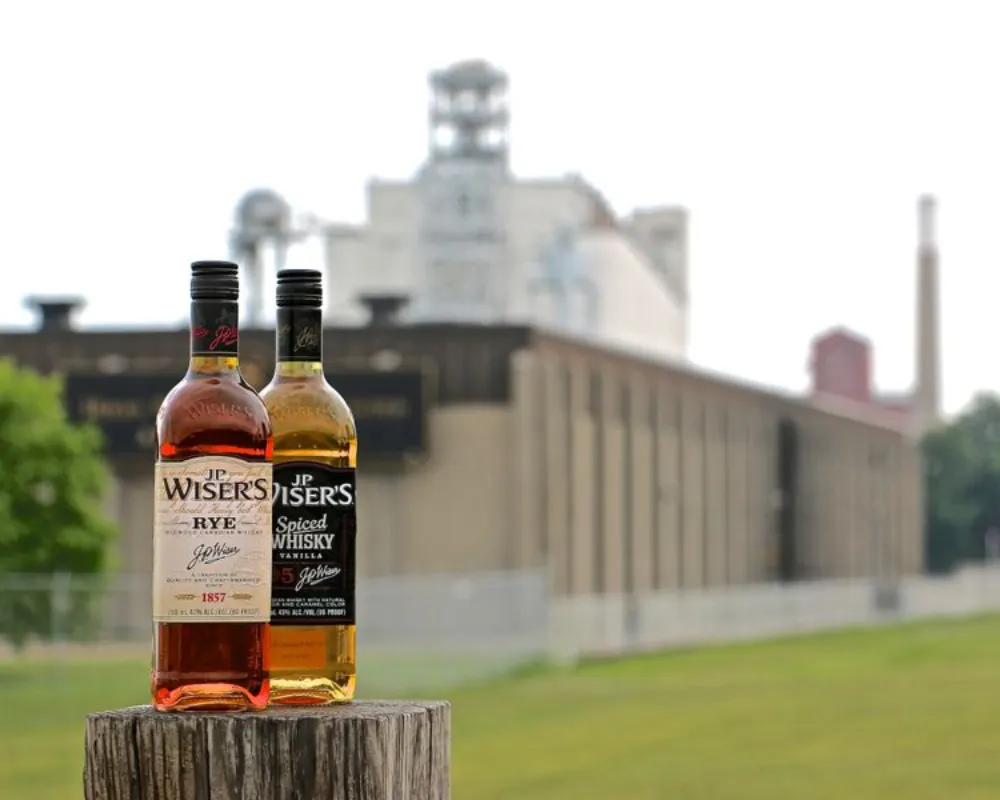 JP Wiser's whiskey bottles on wooden post outdoors.