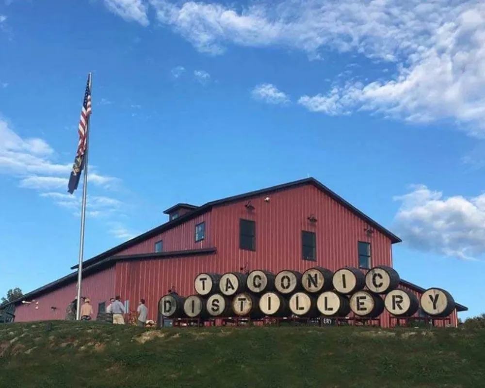 Red distillery building with American flag under blue sky.