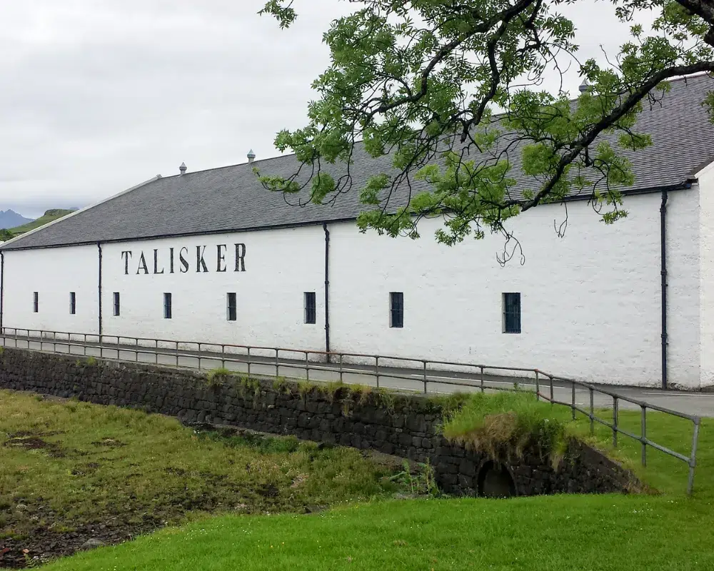 Talisker distillery exterior in Scotland with green landscape.