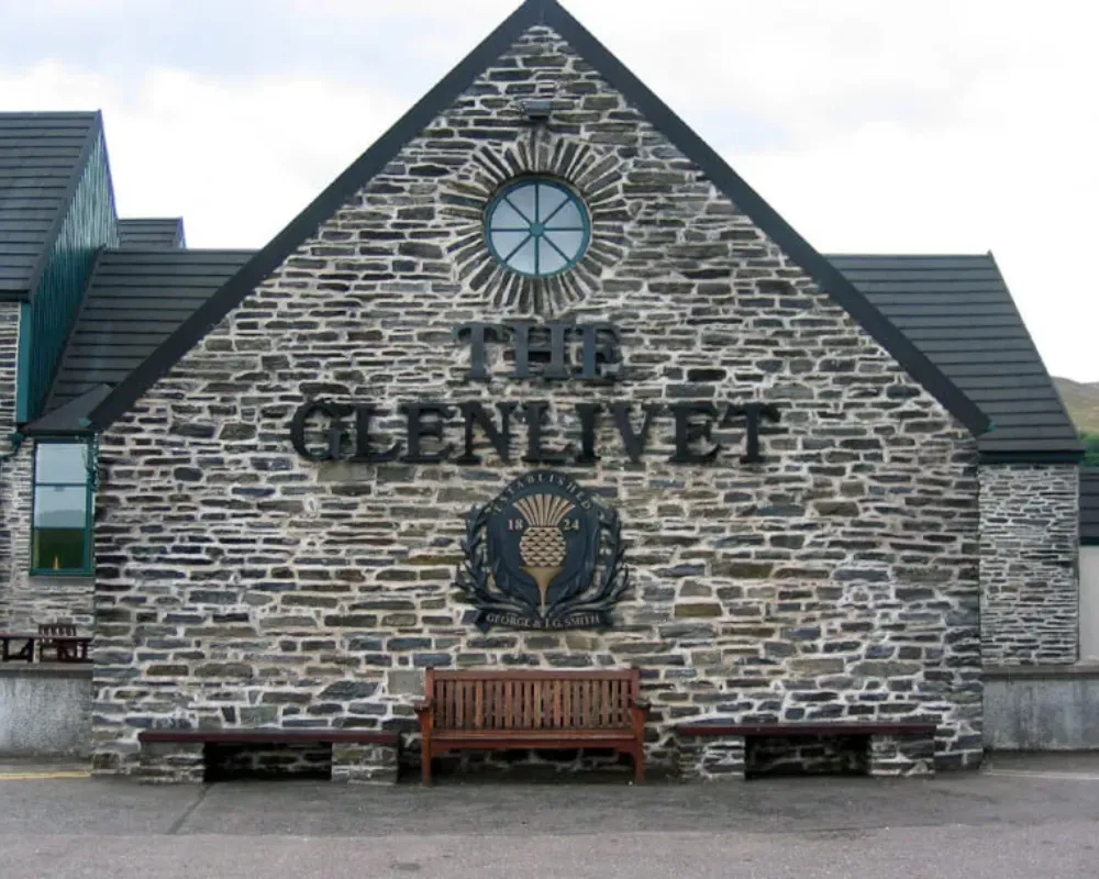 The Glenlivet distillery stone facade with logo and bench.