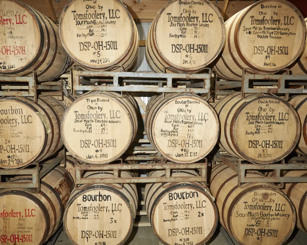 Stacked bourbon whiskey barrels in distillery.