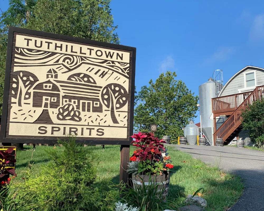 Tuthilltown Spirits distillery sign with landscape and silos.