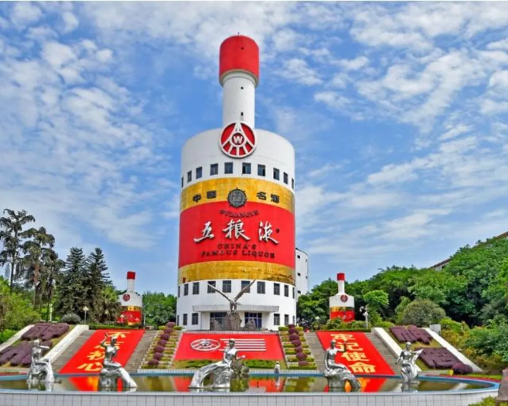 Giant liquor bottle building with sculptures and clear sky.