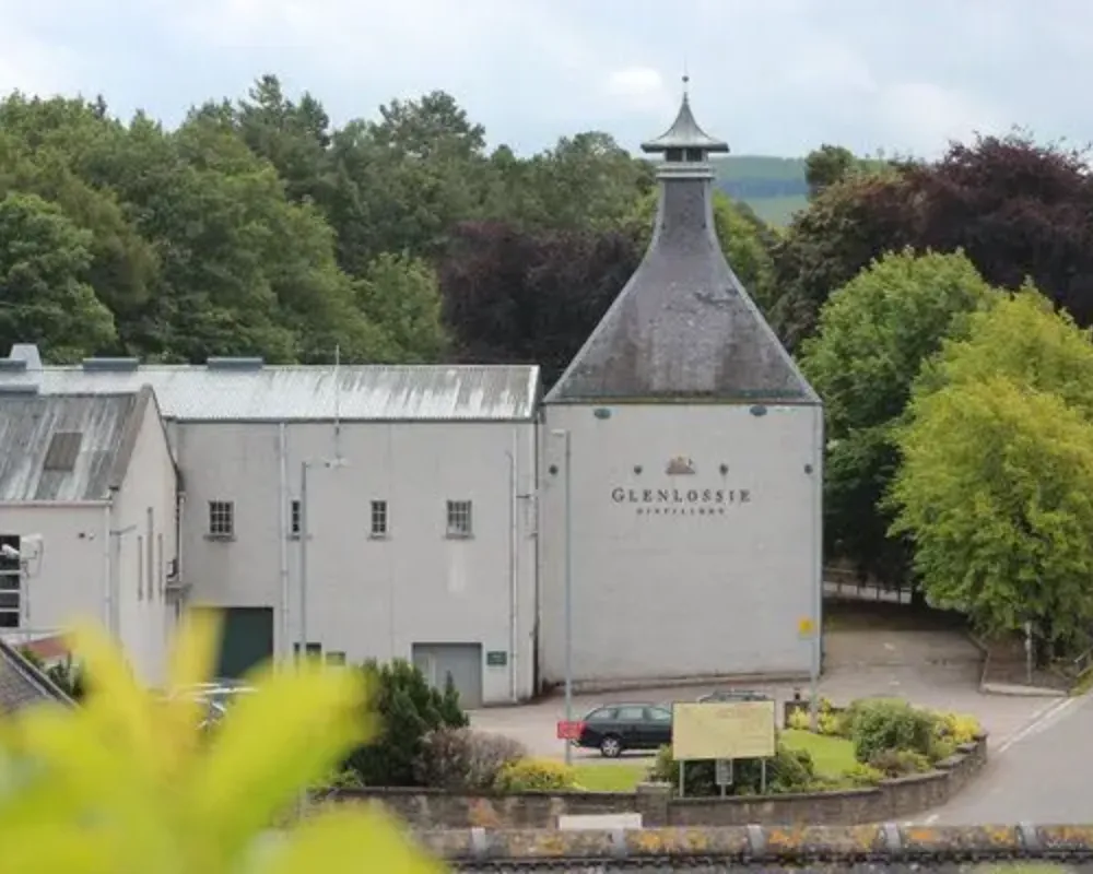 Glenlossie distillery exterior with trees and signage.