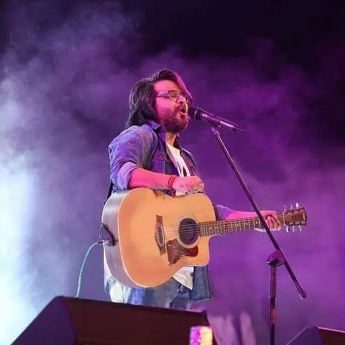 Musician performing live on stage with guitar.