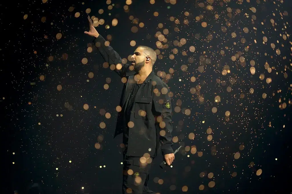 Man performing on stage with lights floating around.