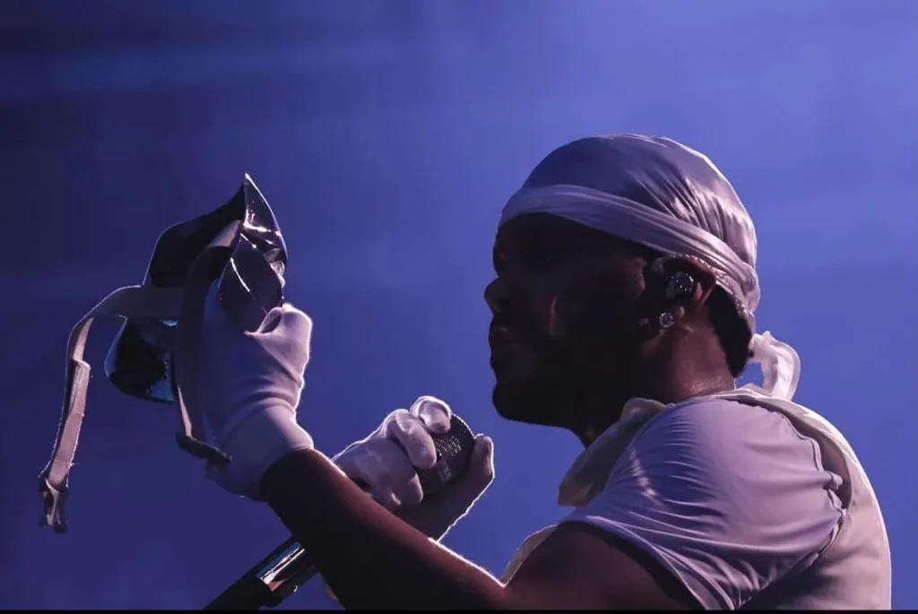 Performer holding mask under blue stage lights.