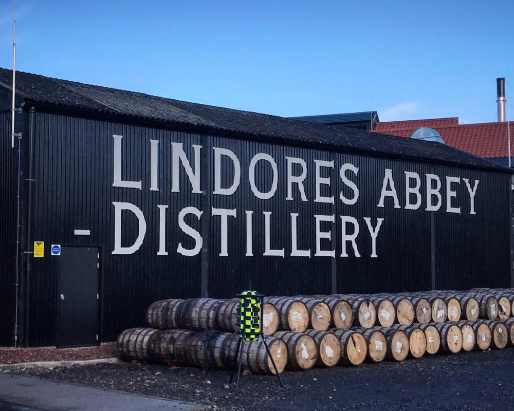 Lindores Abbey Distillery with wooden casks outside building.