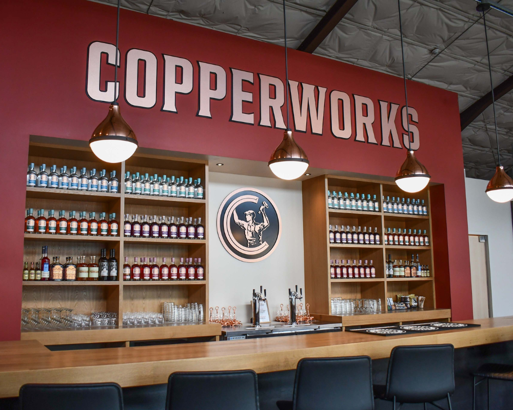 Copperworks bar with liquor bottles and illuminated signs.