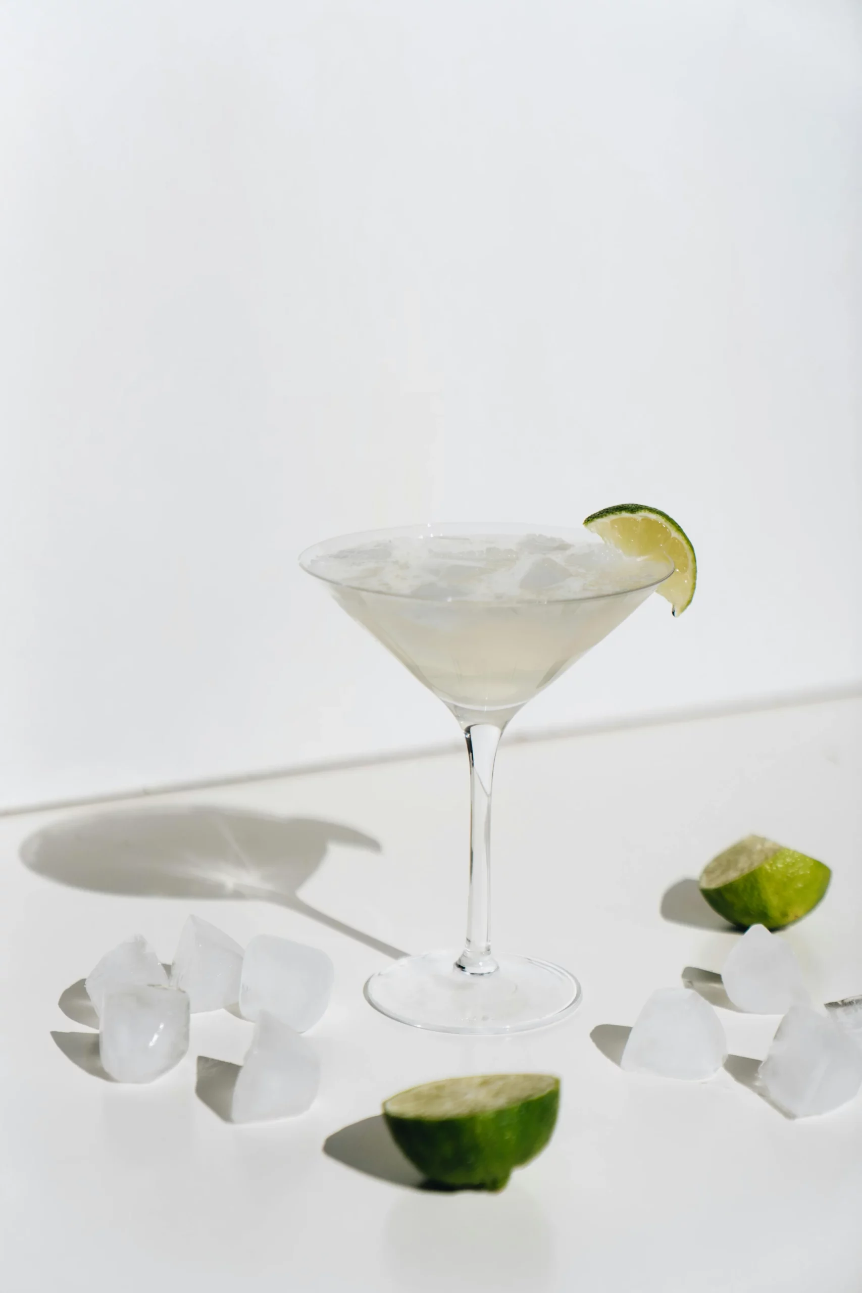 Martini glass with lime and ice cubes.