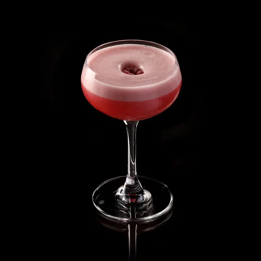 Raspberry cocktail with foam in glass.