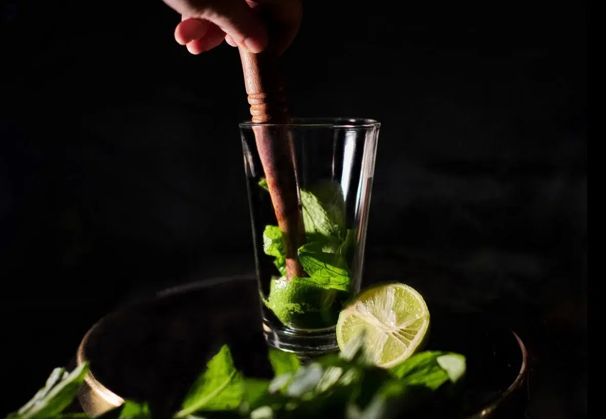 Muddling mint and lime in glass