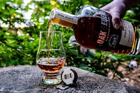 An image of a man pouring finished whiskey into a glass