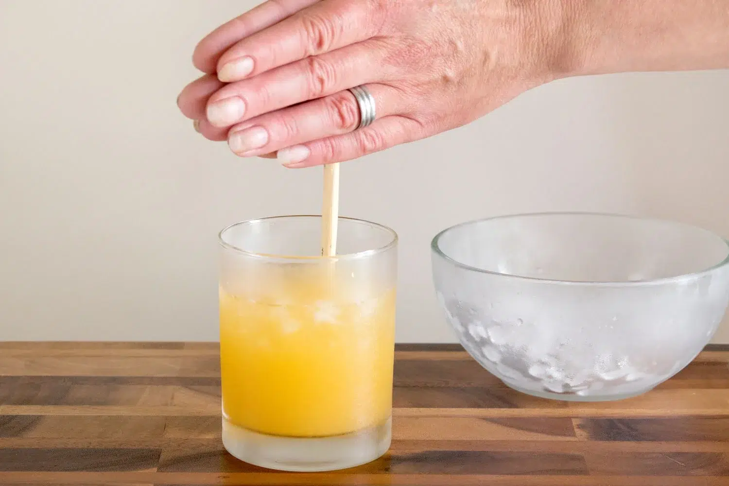 Stirring orange juice with a glass stirring rod.